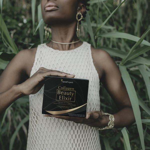 Eine Hand hält eine Packung SanaExpert Collagen Beauty Elixir, eingebettet in einem natürlichen Umfeld mit grünen Pflanzen.