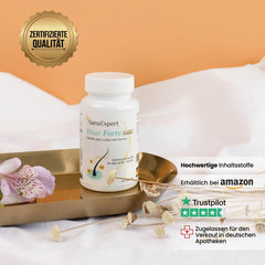 SanaExpert Haar Forte Gold präsentiert auf einem Tablett neben einer Alstroemeria Blüte, Qualitäts- und Vertrauenssiegel deutlich sichtbar.