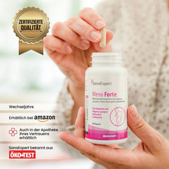 Hand hält eine Kapsel von SanaExpert Meno Forte, vor dem Produktbehälter mit dem Siegel für zertifizierte Qualität, auf hellem Hintergrund.