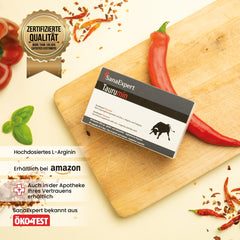 SanaExpert Taurumin Verpackung liegt auf einem Holzschneidebrett neben Basilikum und Chilischoten, Qualitätszertifikat „Mehr als 100.000 zufriedene Kunden“ sichtbar, symbolisiert hochwertige Inhaltsstoffe und Kundenzufriedenheit.