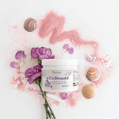 Kreative Darstellung von ElaBeaute Pulver neben einer Dose des Produkts, umgeben von Muscheln und lila Blumen auf einer hellen Oberfläche.