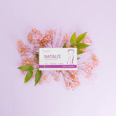 Natalis Pre Box auf einem pastellfarbenen Hintergrund, umgeben von einem zarten Blumenarrangement, sorgt für eine weiche Präsentation.