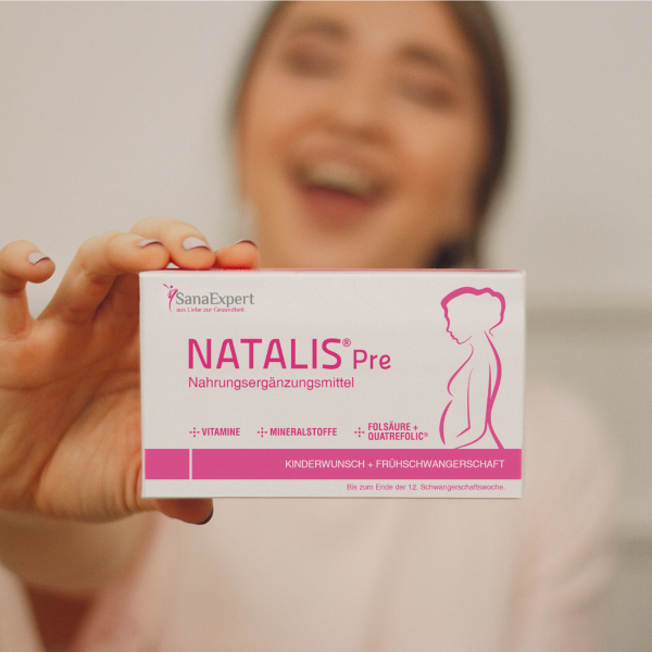 Lachende Frau hält eine Packung NATALIS® Pre in die Kamera.