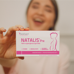 Lachende Frau hält eine Packung NATALIS® Pre in die Kamera.