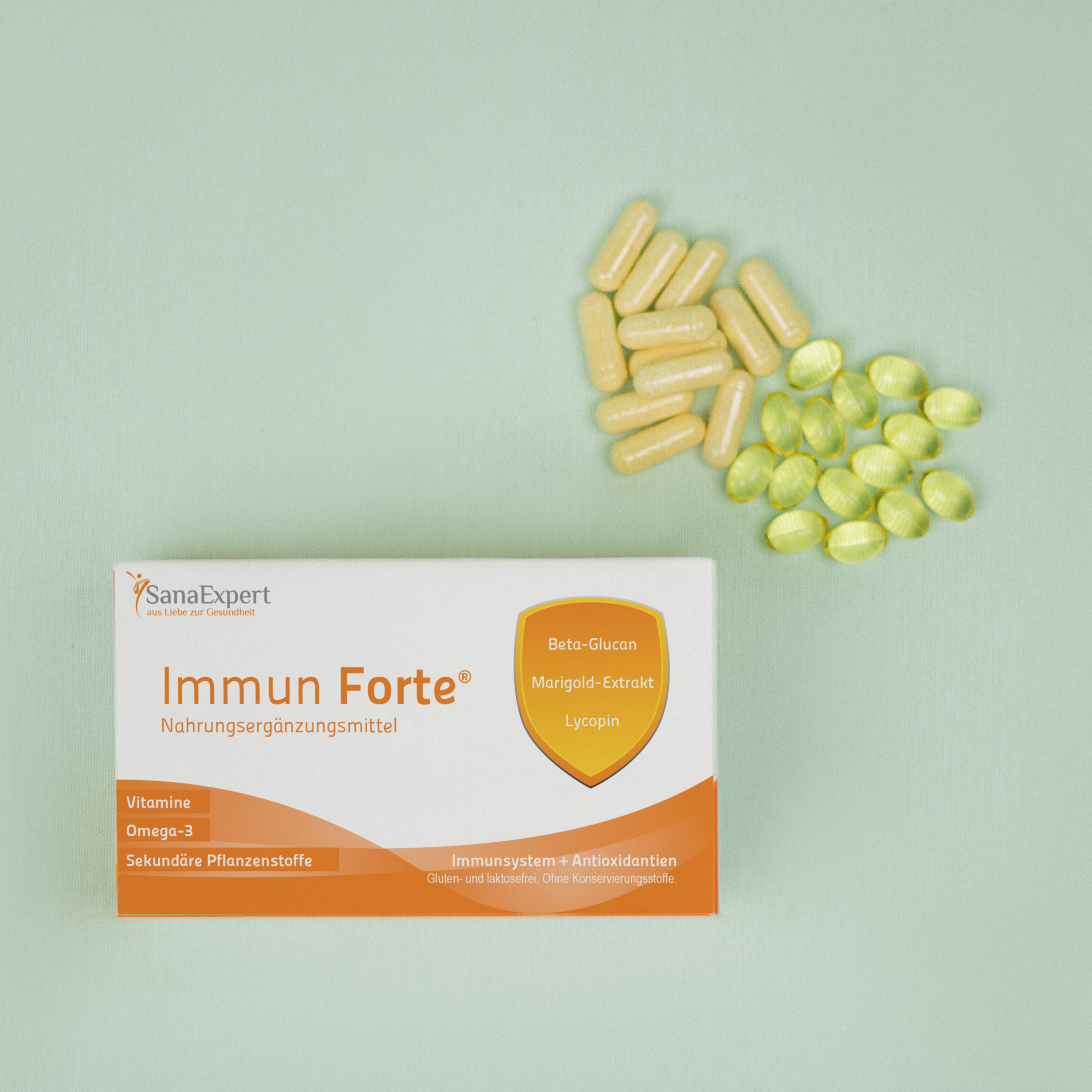 Packung von SanaExpert Immun Forte auf grünem Hintergrund mit einer Streuung von gelben und weißen Kapseln daneben, betont die Gesundheitsvorteile der Inhaltsstoffe wie Beta-Glucan und Lycopin.