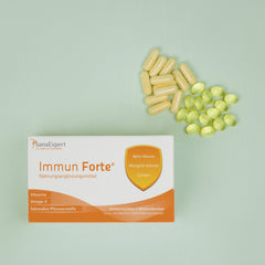 Packung von SanaExpert Immun Forte auf grünem Hintergrund mit einer Streuung von gelben und weißen Kapseln daneben, betont die Gesundheitsvorteile der Inhaltsstoffe wie Beta-Glucan und Lycopin.
