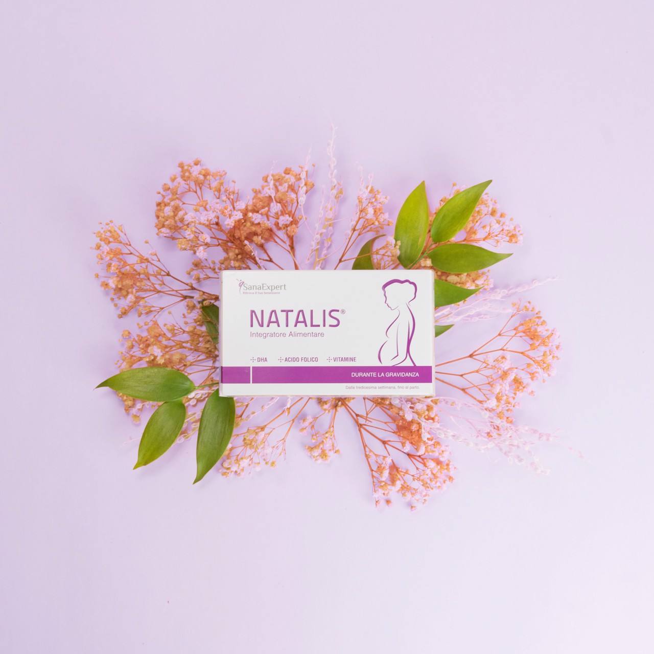 Natalis Pre Box auf einem pastellfarbenen Hintergrund, umgeben von einem zarten Blumenarrangement, sorgt für eine weiche Präsentation.